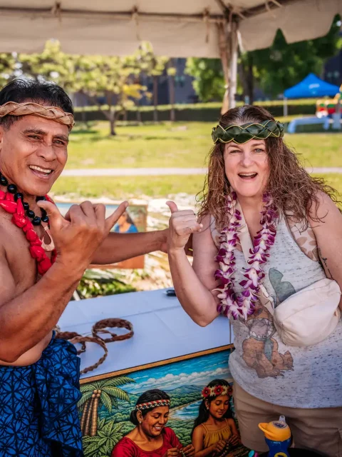 Island host and guest enjoying an interactive game station with bounce houses behind