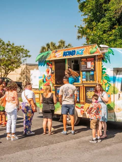 Guests lining up for Hawaiian shaved ice at an outdoor company luau